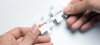 two puzzle pieces one for rently another for Knock CRM being put together by a pair of hands