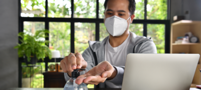 man is wearing a mask while dispensing some hand sanitizer onto his hand