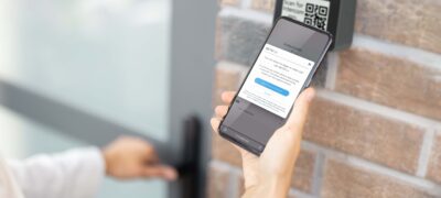 Person using smartphone to access virtual resident directory at a building entrance